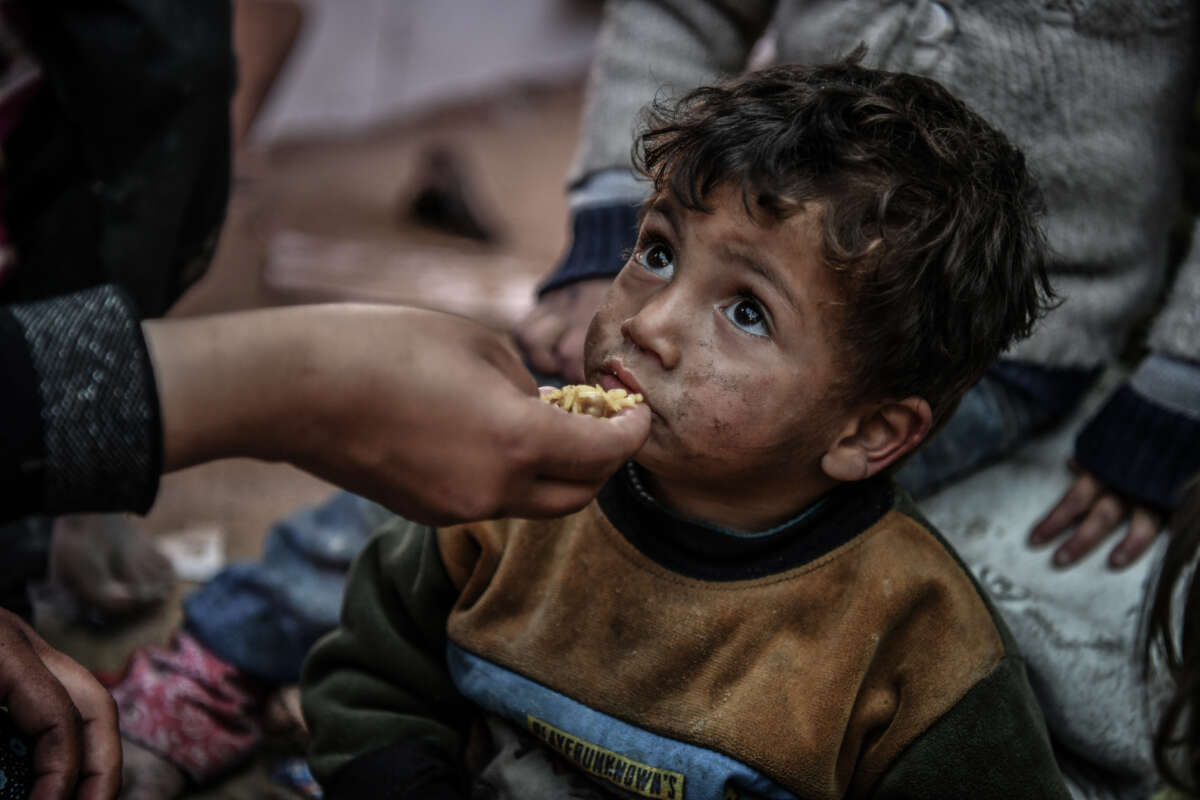 A Palestinian mother feeds her child near a makeshift tent as the Palestinian families seek refuge at the El-Mavasi district as they struggle to find clean water, food and medicine as the Israeli attacks continue in Rafah, Gaza, on February 9, 2024.