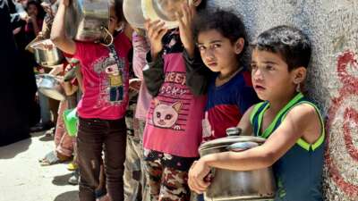 Children in Rafah queue to receive a bowl of food for their families from charity organizations, in Rafah, Gaza, on May 3, 2024.
