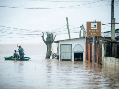 Two men ride a boat at Praia do Lami as it rains in a flood affected area on May 10, 2024, in Porto Alegre, Brazil.