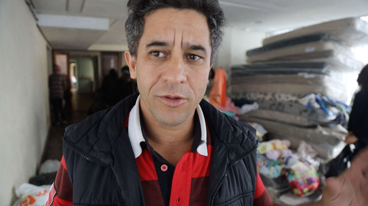 Anselmo Gomes stands inside the housing occupation, while residents receive donations in late May.