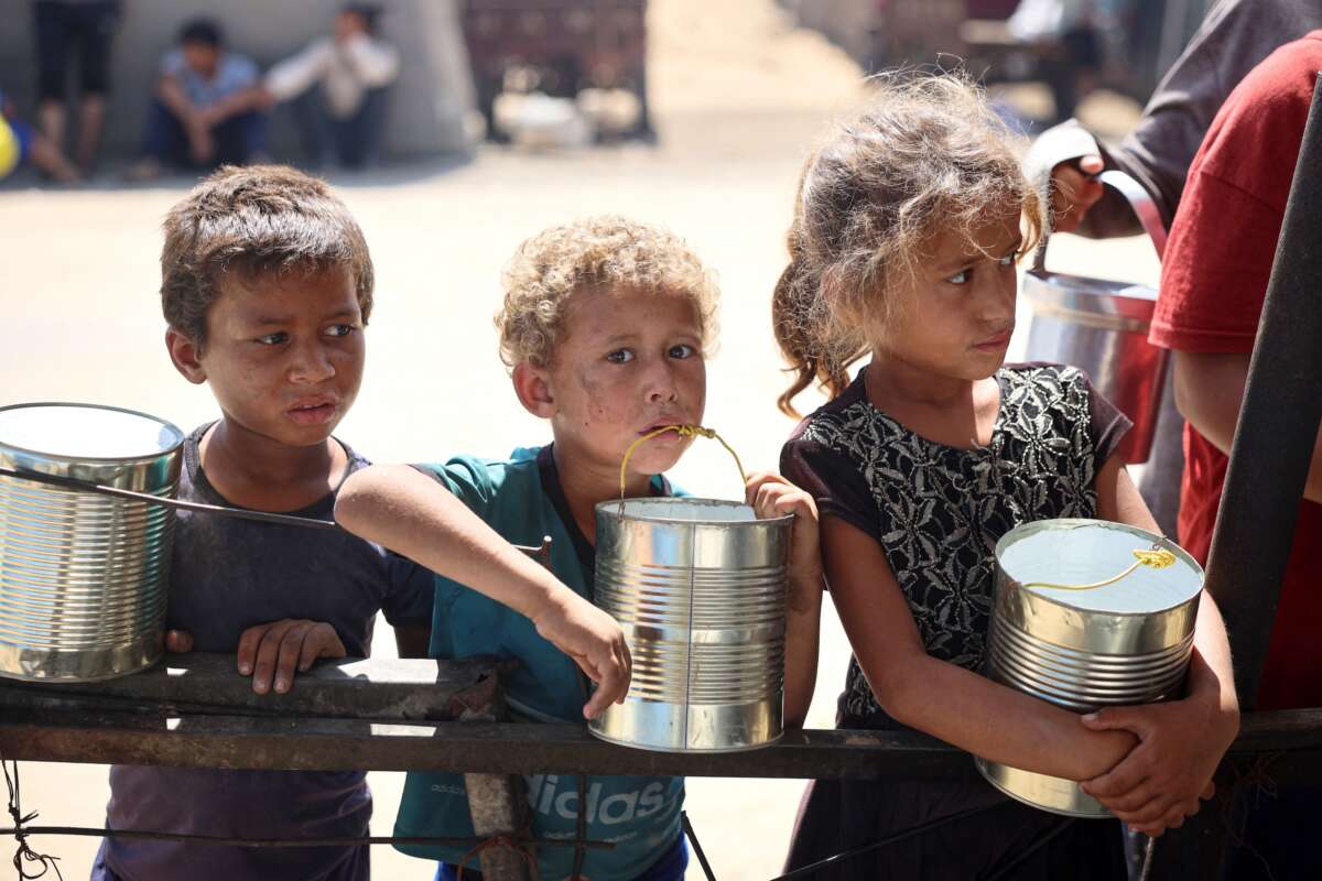 Children wait for food being distributed at a camp for internally displaced people where they live due to the Israeli bombardment of the Gaza Strip, in Khan Yunis, in the southern Gaza Strip on June 11, 2024.