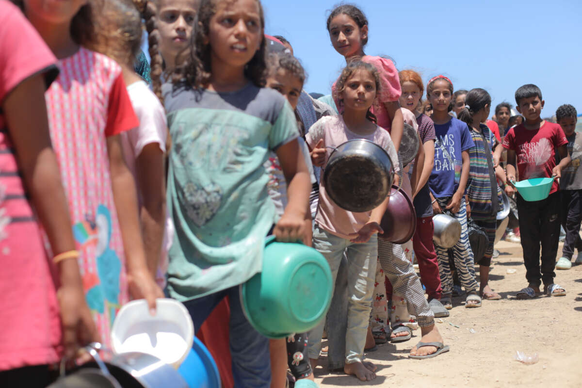 Palestinians, including children, wait in line to receive food distributed by charitable organizations amidst Israeli attacks in Deir Al- Balah, Gaza, on May 28, 2024.