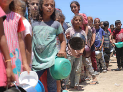 Palestinians, including children, wait in line to receive food distributed by charitable organizations amidst Israeli attacks in Deir Al- Balah, Gaza, on May 28, 2024.