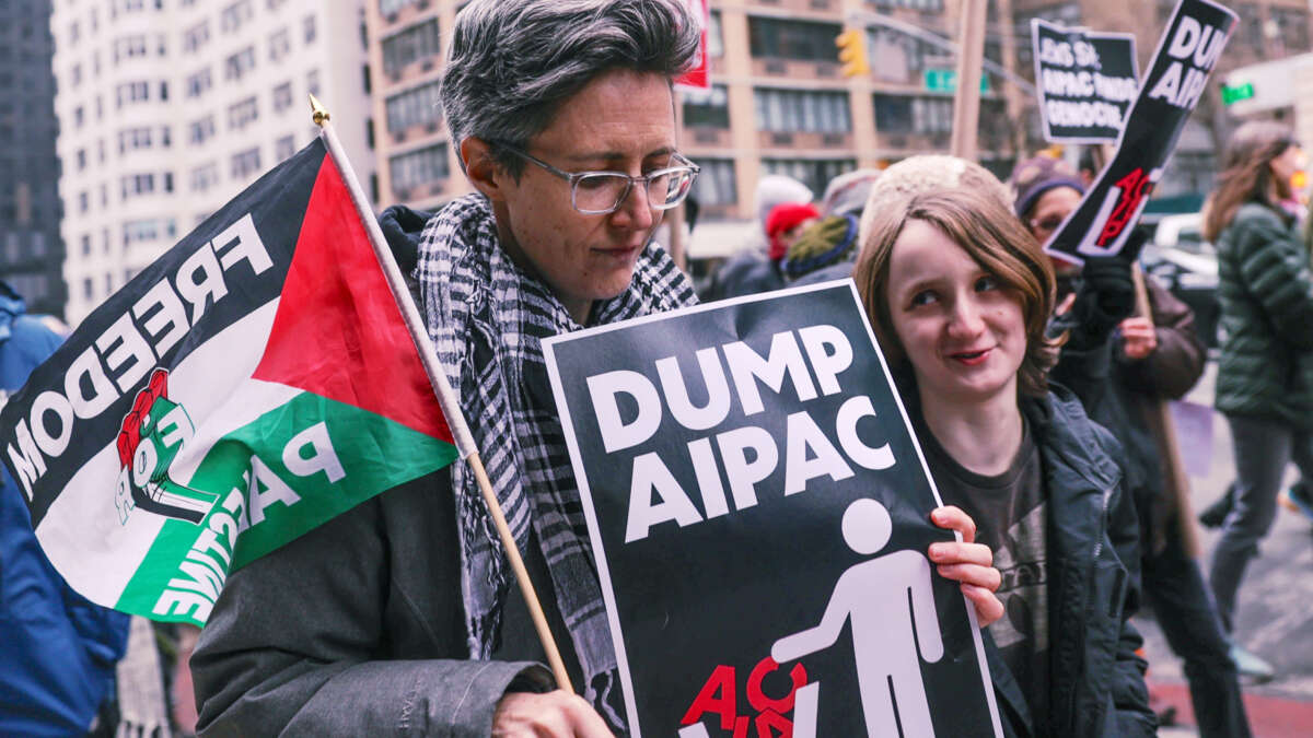 A protester holds a sign reading "DUMP AIPAC" during an outdoor protest