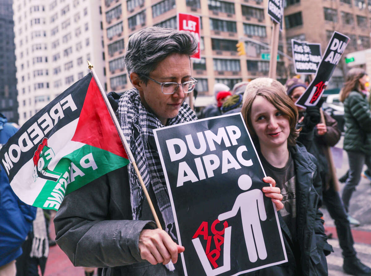 A protester holds a sign reading "DUMP AIPAC" during an outdoor protest