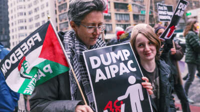 A protester holds a sign reading "DUMP AIPAC" during an outdoor protest