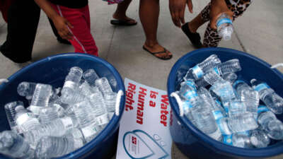 People stand over bottles of water as demonstrators protest against the Detroit Water and Sewer Department July 18, 2014, in Detroit, Michigan.