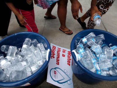 People stand over bottles of water as demonstrators protest against the Detroit Water and Sewer Department July 18, 2014, in Detroit, Michigan.