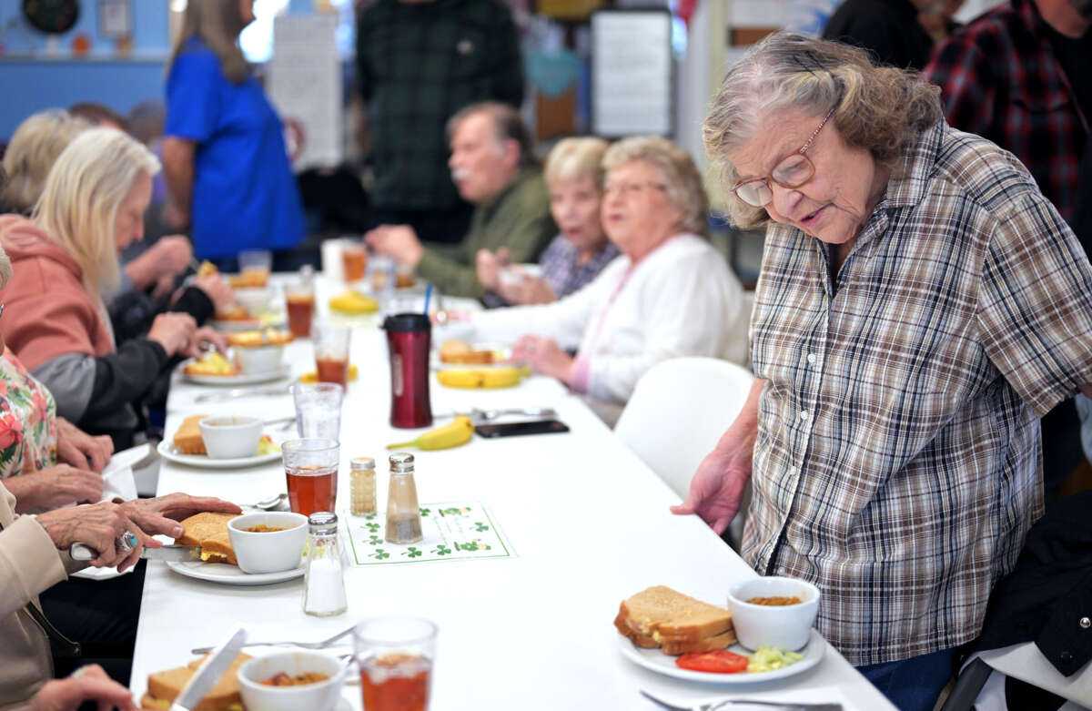 Elderly people gather together to eat at a table