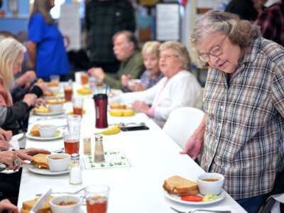 Elderly people gather together to eat at a table