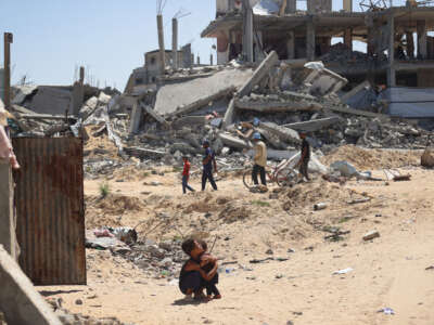 A Palestinian child hugs a toddler surrounded by destroyed buildings in Khan Yunis, in the southern Gaza Strip, on June 11, 2024.