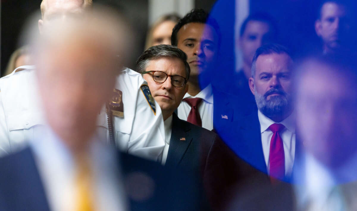 Speaker of the House Mike Johnson (center) listens as former President Donald Trump sits next to his lawyers as he arrives for his trial at Manhattan Criminal Court on May 14, 2024, in New York City.