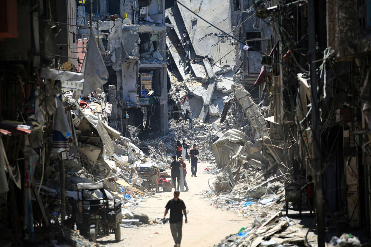 Palestinian men walk along a narrow street past destroyed buildings in Khan Yunis, in the southern Gaza Strip on June 11, 2024, amid the ongoing conflict between Israel and the Palestinian Hamas militant group.