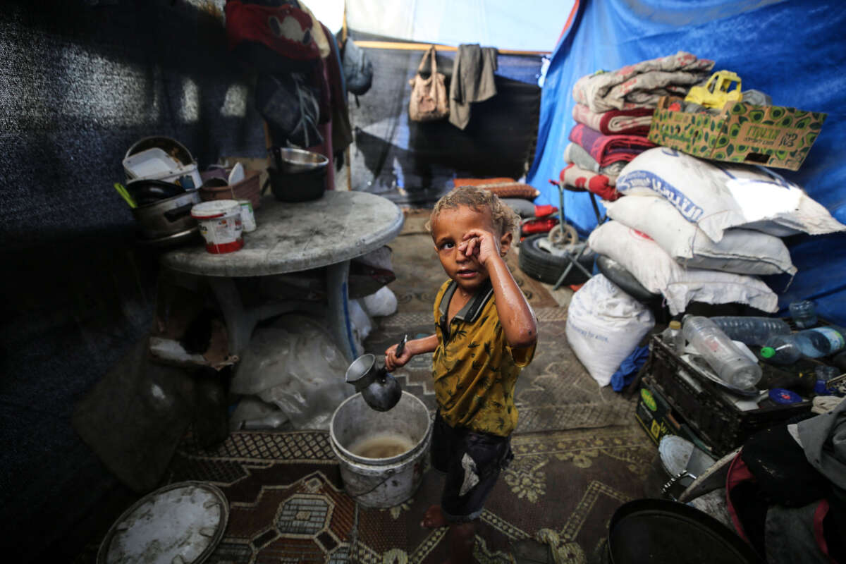 A displaced Palestinian boy is splashing his face with water in front of his tent during a heatwave in Deir al-Balah, in the central Gaza Strip, on June 11, 2024.