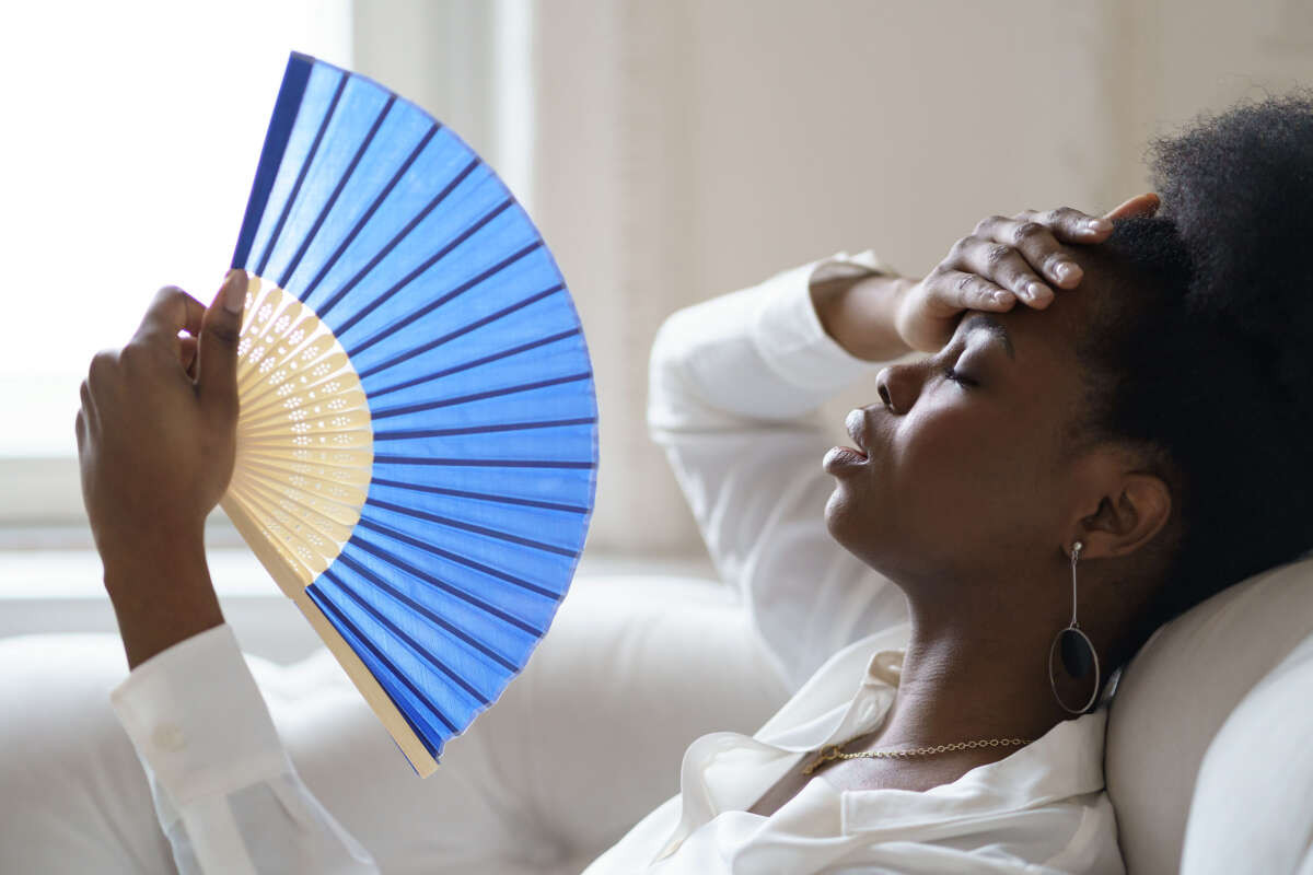 Woman fans herself to cool off from heat