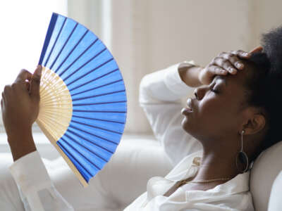 Woman fans herself to cool off from heat