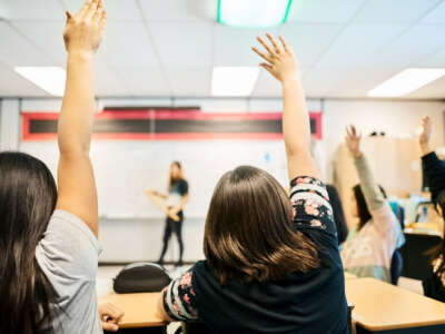 Students raise hands in classroom