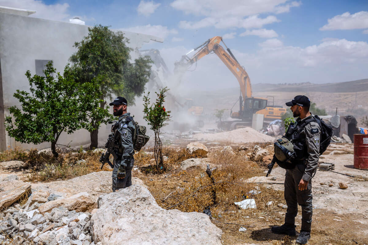 IDF soldiers watch as a Palestinian's home is demolished