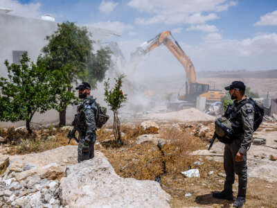 IDF soldiers watch as a Palestinian's home is demolished