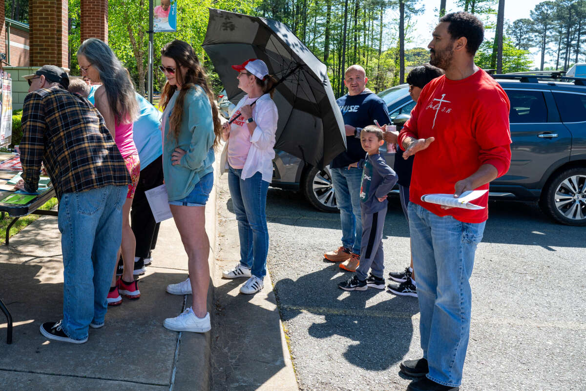 Caroline Morgan, a volunteer with Progressive Arkansas Women, holds an umbrella to block anti-abortion demonstrators as people sign petitions at an event at the Saline County Library in Bryant, Arkansas, on April 13, 2024.