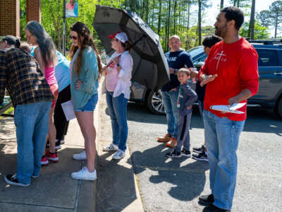 Caroline Morgan, a volunteer with Progressive Arkansas Women, holds an umbrella to block anti-abortion demonstrators as people sign petitions at an event at the Saline County Library in Bryant, Arkansas, on April 13, 2024.