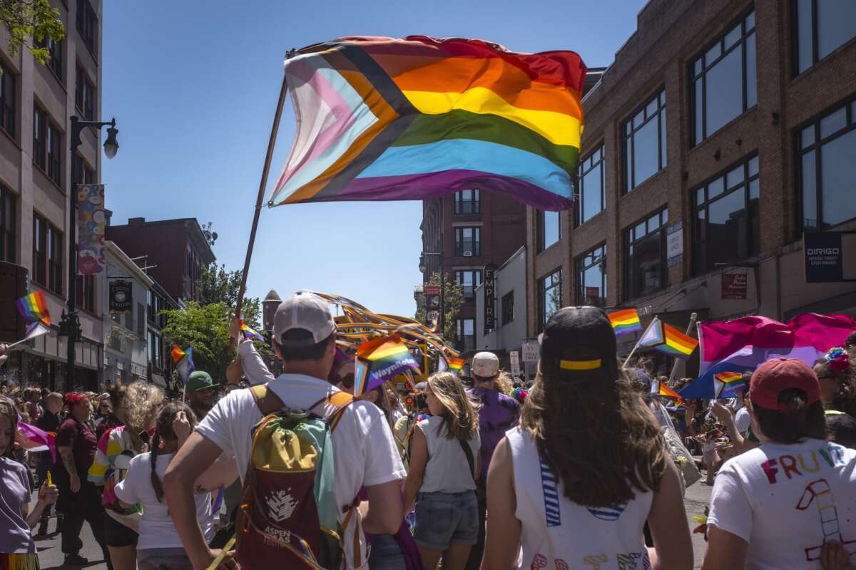 The Progress Pride Flag flies above a crowd during the Pride parade in Portland, Maine, on June 15, 2024.