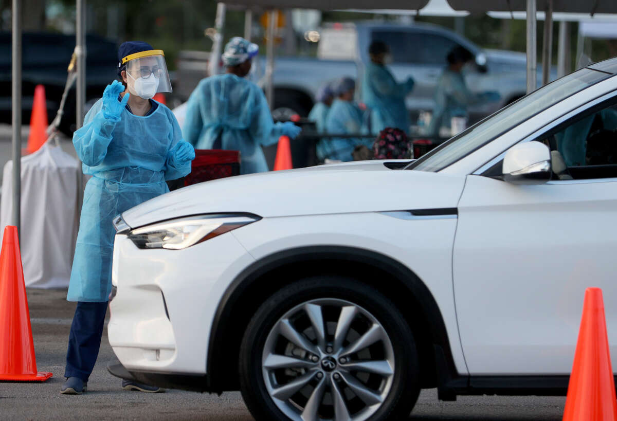 A health care worker at a 24-hour drive-through site set up by Miami-Dade County and Nomi Health in Tropical Park prepares to administer a COVID-19 test on August 30, 2021, in Miami, Florida.