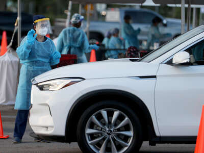 A health care worker at a 24-hour drive-through site set up by Miami-Dade County and Nomi Health in Tropical Park prepares to administer a COVID-19 test on August 30, 2021, in Miami, Florida.