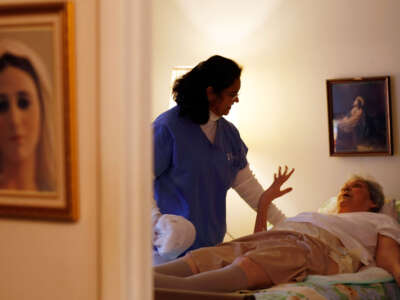 A United HomeCare Services home health aide, Wendy Cerrato, helps Olga Socarras get dressed during a visit on January 6, 2010, in Miami, Florida.