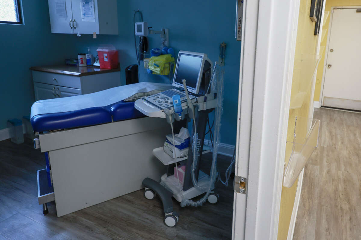 A clinic bed with various medical items is seen in an abortion clinic exam room