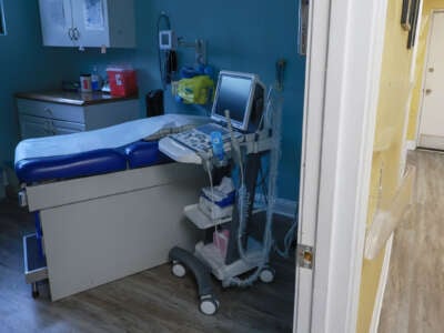 A clinic bed with various medical items is seen in an abortion clinic exam room
