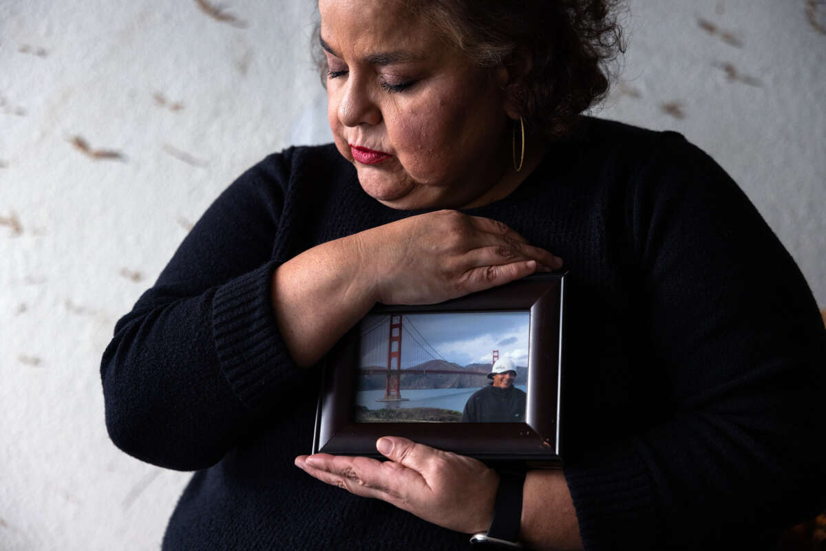 Sandra Muñoz sits for a portrait and holds a photo of her husband