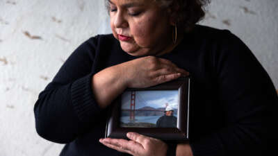 Sandra Muñoz sits for a portrait and holds a photo of her husband
