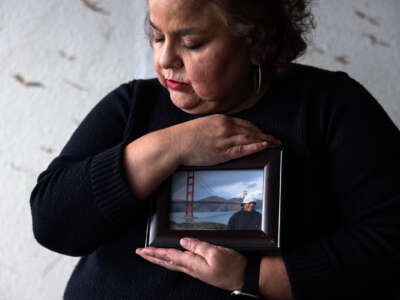 Sandra Muñoz sits for a portrait and holds a photo of her husband