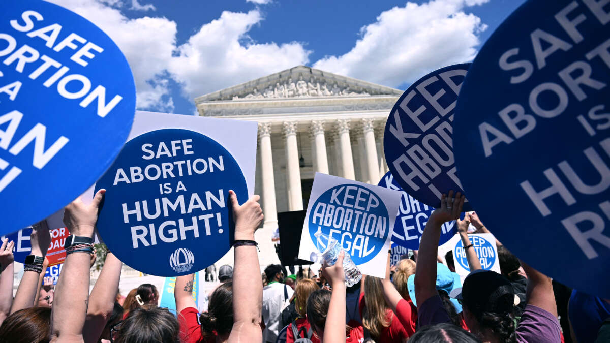 People hold signs reading "KEEP ABORTION LEGAL" and "SAFE ABORTION IS A HUMAN RIGHT" during a protest on the steps of the U.S. Supreme Cort building