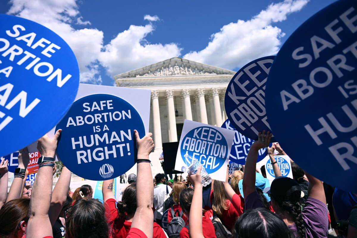 People hold signs reading "KEEP ABORTION LEGAL" and "SAFE ABORTION IS A HUMAN RIGHT" during a protest on the steps of the U.S. Supreme Cort building