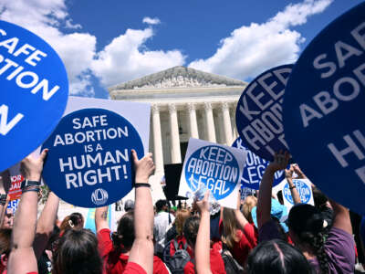 People hold signs reading "KEEP ABORTION LEGAL" and "SAFE ABORTION IS A HUMAN RIGHT" during a protest on the steps of the U.S. Supreme Cort building