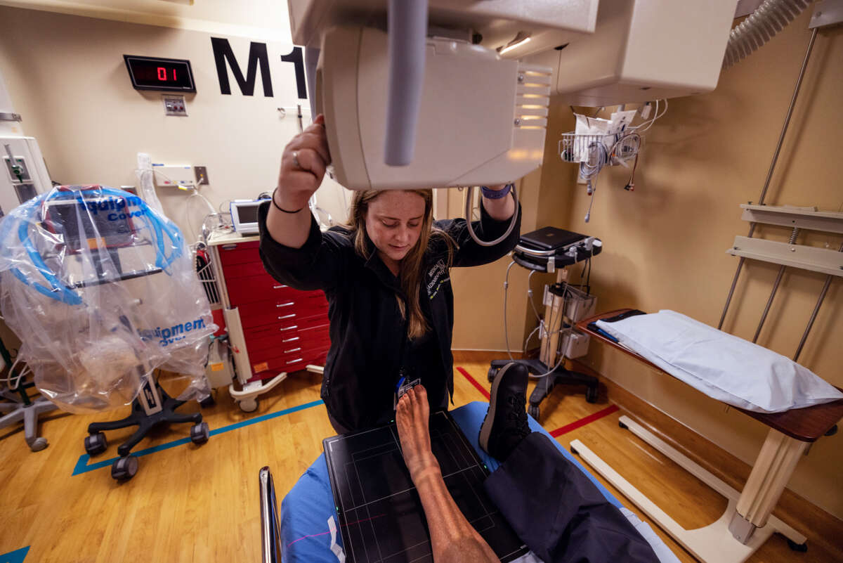 A medical worker prepares a patient for a leg x-ray