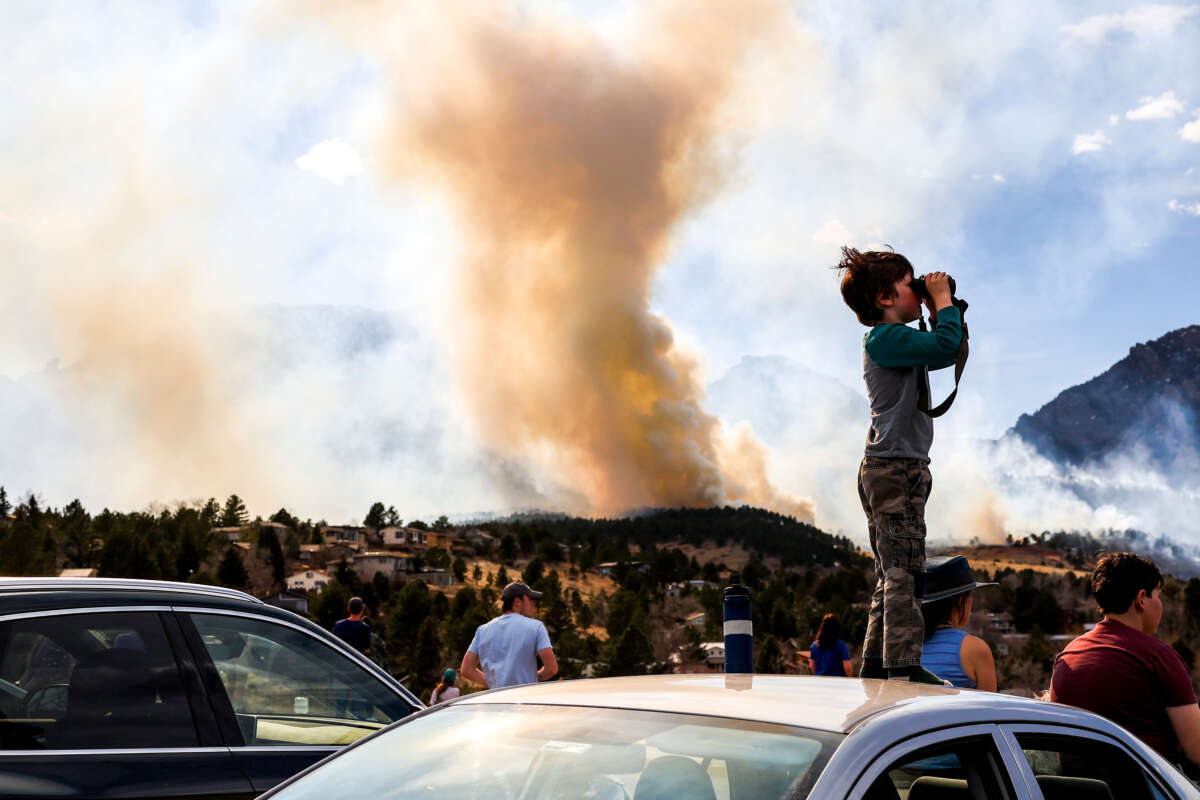 Amitai Beh, 6, watches the NCAR fire through binoculars on March 26, 2022, in Boulder, Colorado.