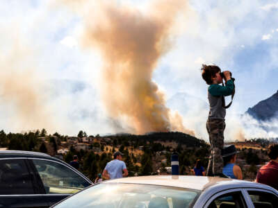 Amitai Beh, 6, watches the NCAR fire through binoculars on March 26, 2022, in Boulder, Colorado.