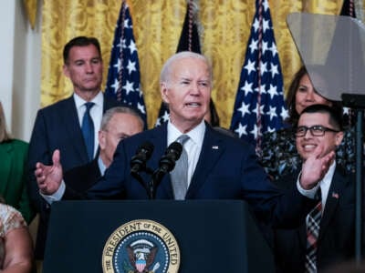 Joe Biden speaks at a podium as supporters stand behind him
