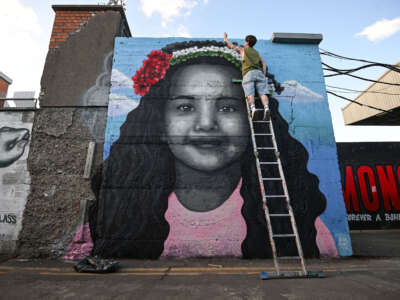 Artist Emmalene Blake puts the final touches to a mural of Hind Rajab, the 6-year-old Palestinian girl who was killed in Gaza, along with several family members and paramedics, outside the ground before the international solidarity match between Bohemians and Palestine at Dalymount Park in Dublin, Ireland, on May 15, 2024.