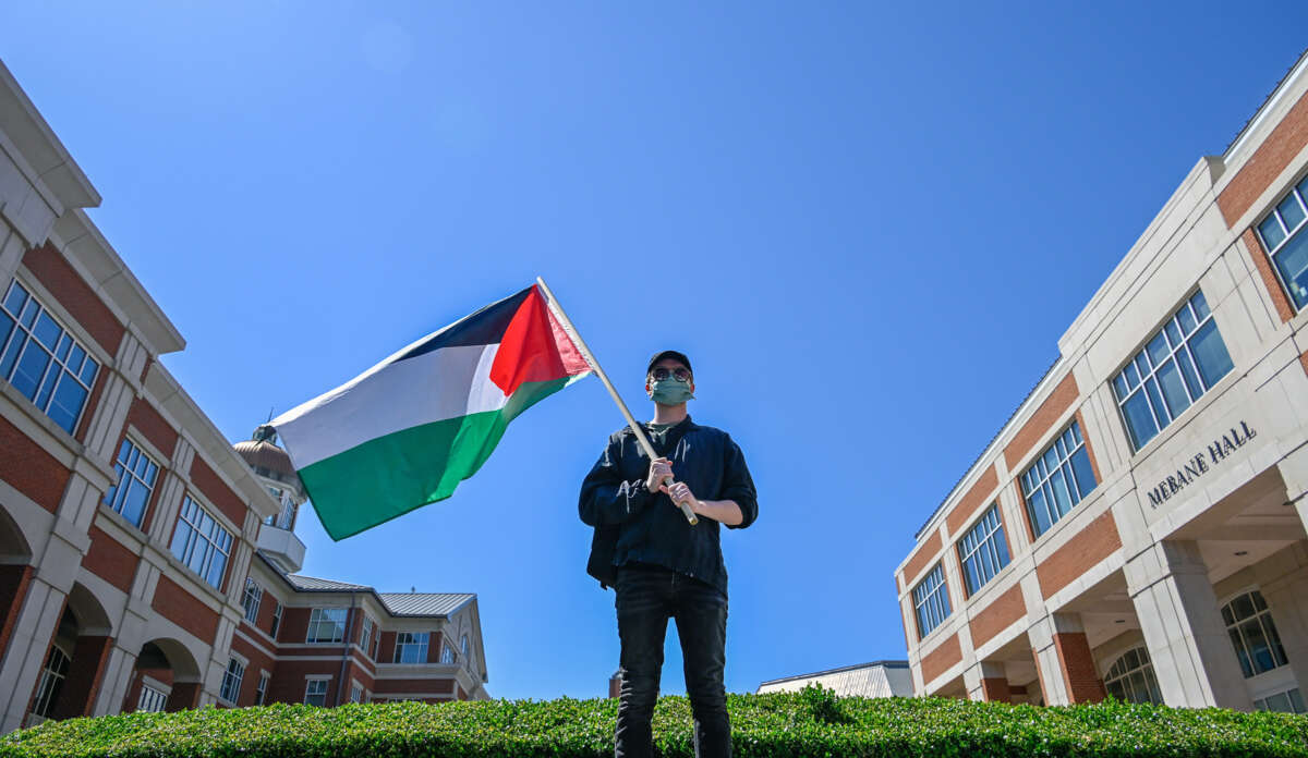 A lone protester holds a Palestinian flag on a University campus