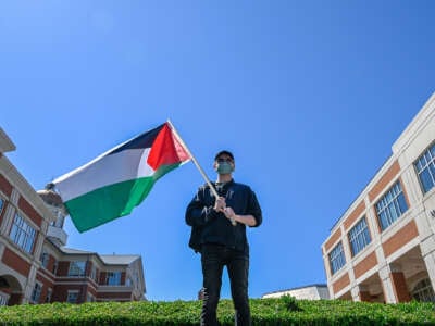 A lone protester holds a Palestinian flag on a University campus
