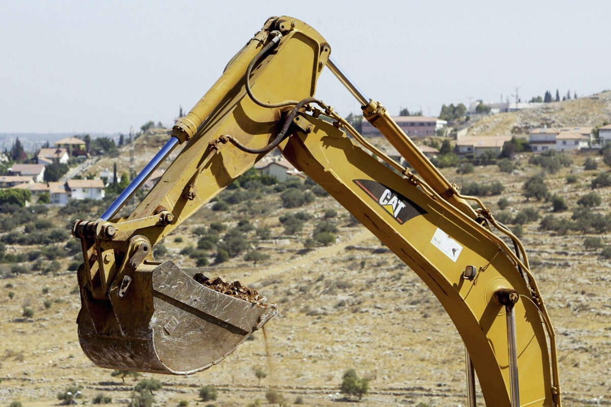 An Israeli contractor's Caterpillar 330B LME hydraulic excavator grabs a load of soil and rocks as it clears the path of Israel's separation fence on Palestinian land on July 1, 2004, in the West Bank village of Az-Zawiya.
