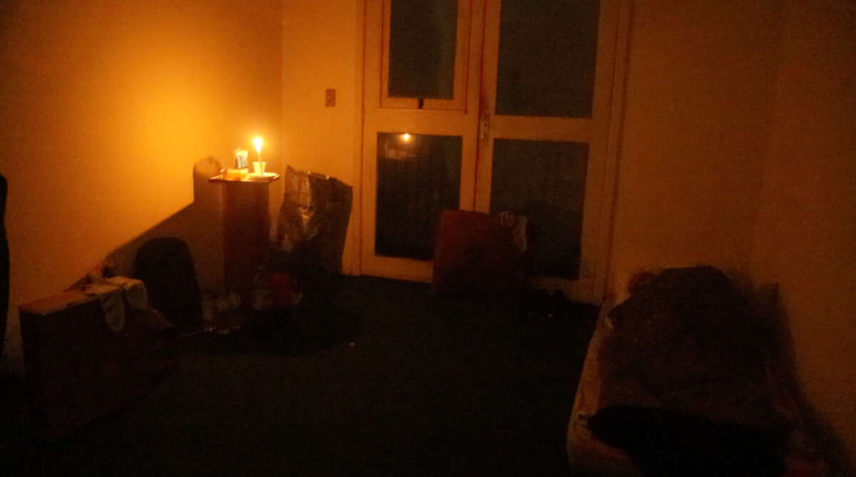 A single candle lights on one room in the housing occupation, as one resident sleeps in the corner.