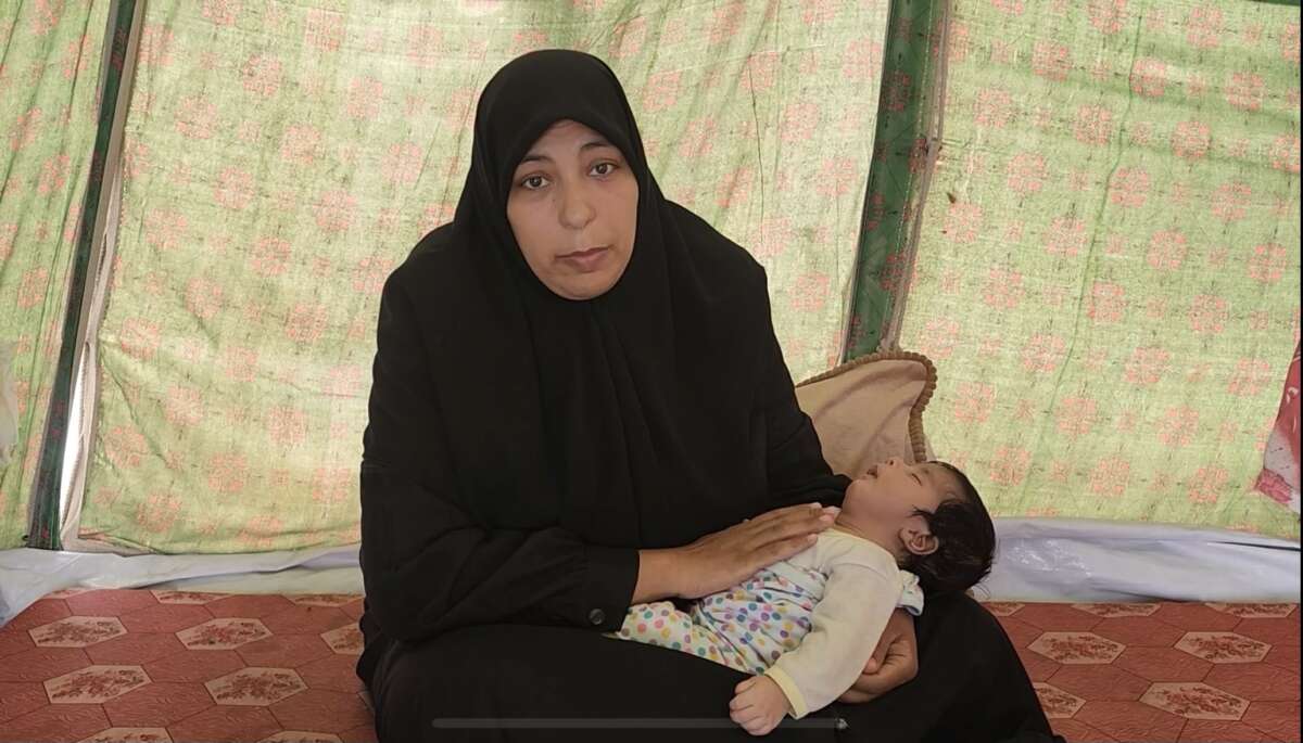 Mustafa being held by his mother in their makeshift tent.