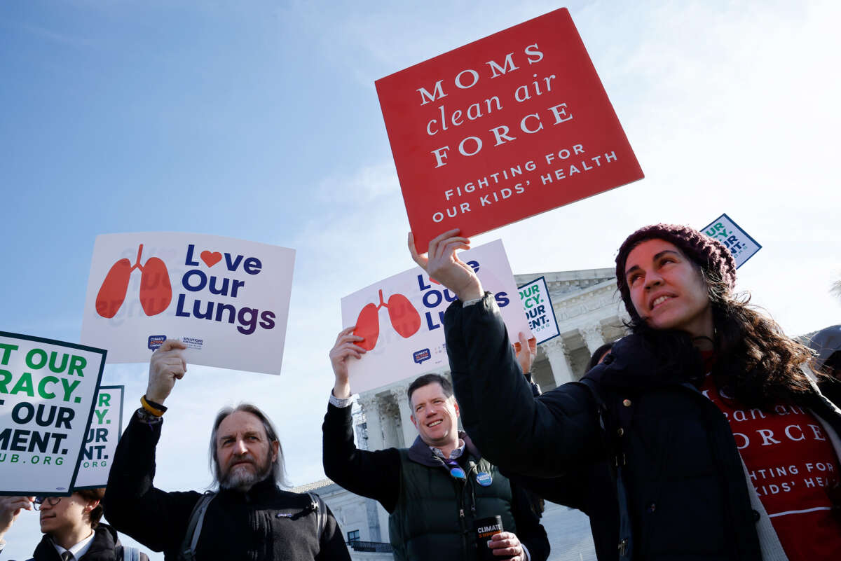 People hold up signs reading "MOMS CLEAN AIR FORCE; FIGHTING FOR OUR KIDS' HEALTH" and "LOVE OUR LUNGS" during a protest outside of the U.S. Supreme Court building