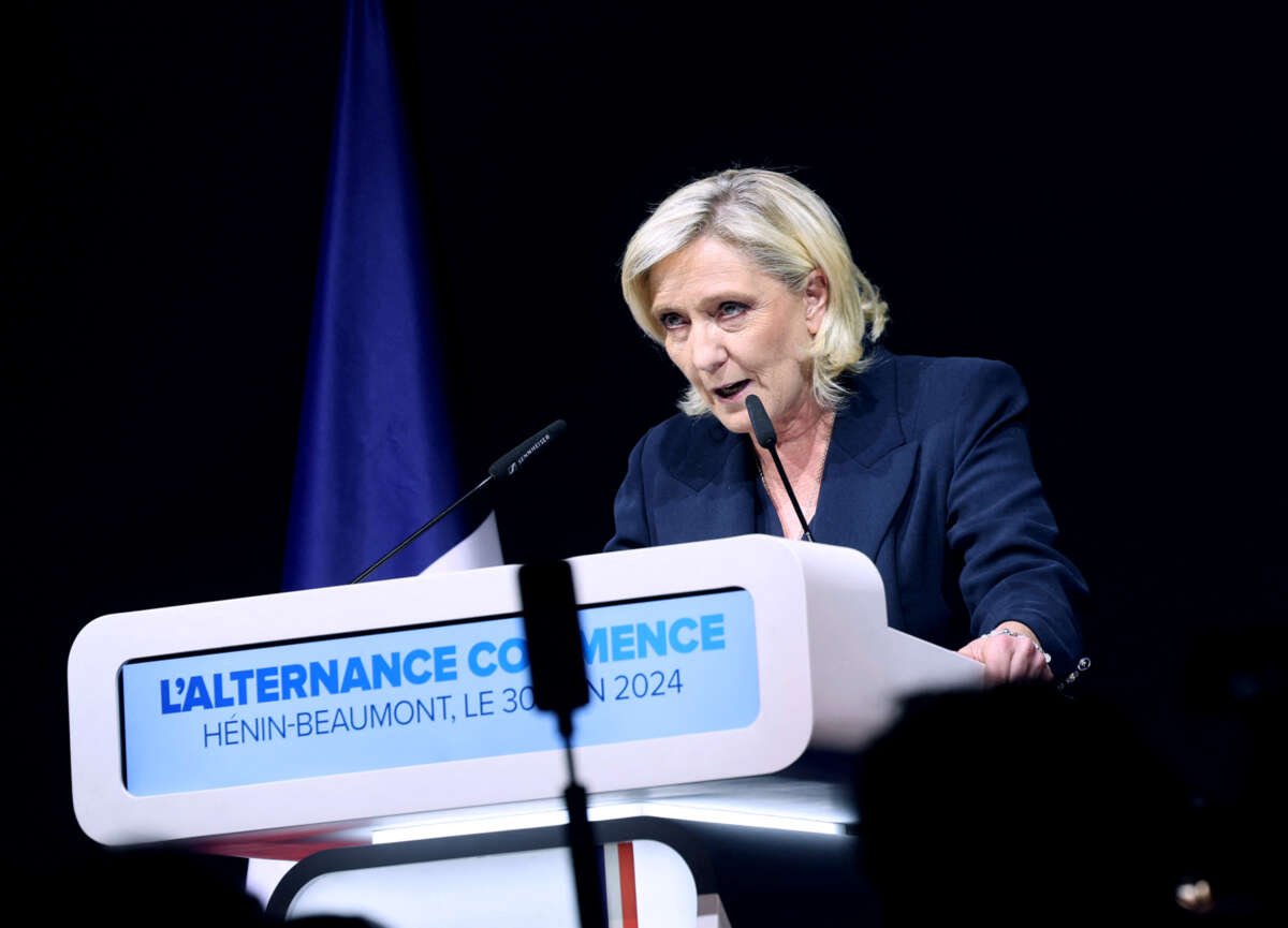Marie Le Pen speaks into a microphone at a podium