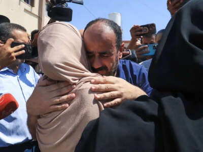 Al-Shifa hospital director Mohammed Abu Salmiya embraces a woman in a beige hijab as supporters surround them
